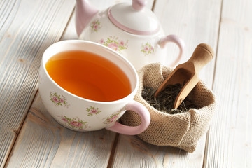 Cup of tea and teapot and dried leaves of tea