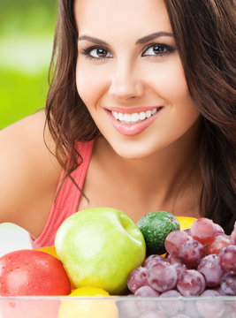 smiling woman with plate of fruits, outdoor