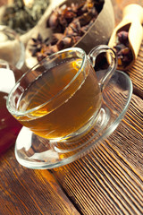 Assorted tea leaves, cup of tea and teapot on wood