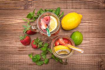 Refreshing summer drink with strawberry in glass jars on a wooden background.