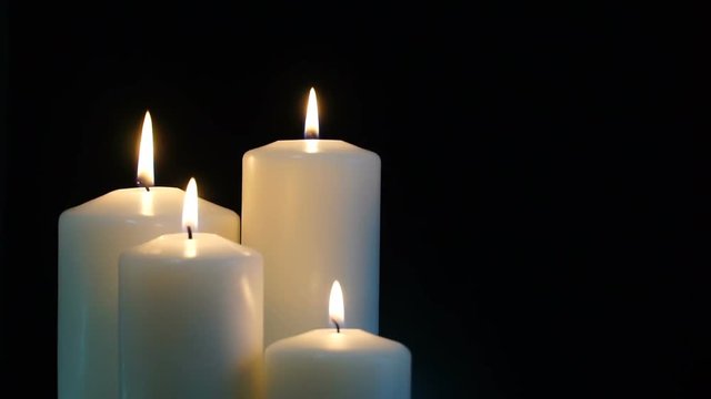 footage burning candles isolated on a black background. 