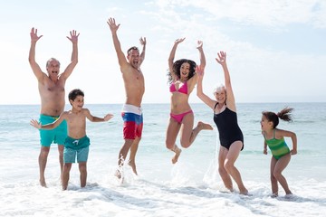 Happy multi genration family jumping at beach 