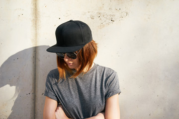 Female model wearing a black blank cap and sunglasses looking away. Portrait of a young beautiful girl with cap - 109788608
