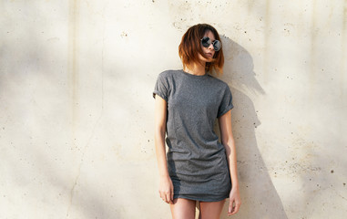 beautiful young girl wearing in a gray blank t-shirt and sunglasses posing against a background of...
