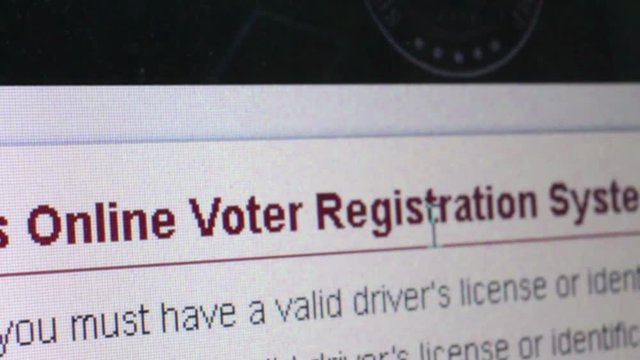 Macro close up of  computer monitor reading Online Voter Registration, with user moving cursor nearby.