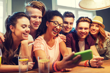happy friends with smartphone taking selfie at bar