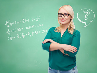 happy woman in eyeglasses over school blackboard
