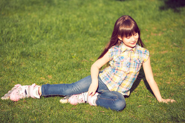 Fototapeta premium girl wearing roller skates sitting on grass in the park.
