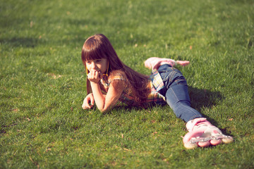 girl wearing roller skates sitting on grass in the park.