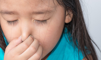 close up of a girl holding her nose because of a bad smell.