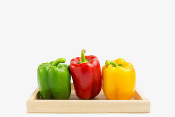 Fresh green, yellow and red pepper on wood box, including with c