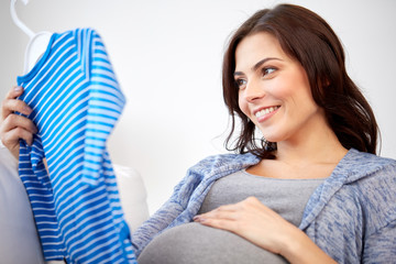 Fototapeta premium happy woman holding baby boys bodysuit at home