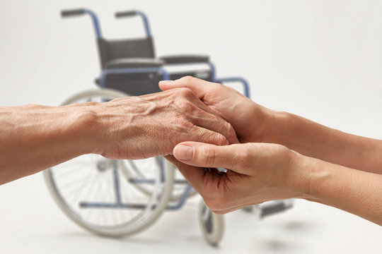 Wwheelchair. Hands of an elderly man holding the hand of a woman