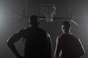 Two basketball player looking the basketball hoop