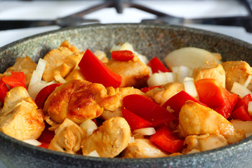 Обжаренные куски курицы с болгарским перцем и луком на сковороде