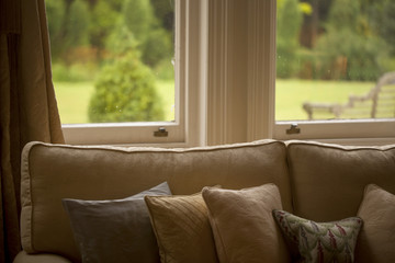 View Through the Window. A comfortable lounge is a good place to sit out of the weather on a typically wet spring day in England. Through the window is a green and lush wet spring garden.