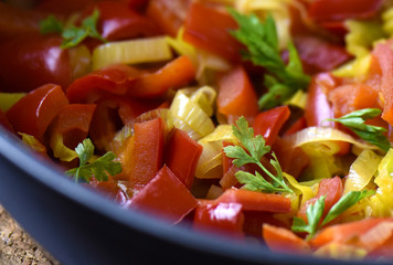 Mixed fresh vegetables (pepper, leek, herbs) in a skillet