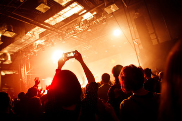 A man holding a smartphone during a concert