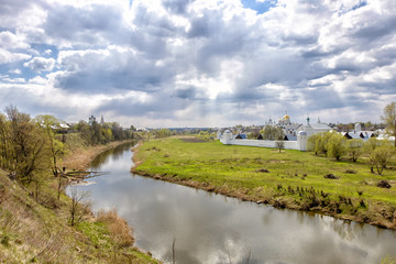 Fototapeta na wymiar Landscape with cloudy sky, river, field and church