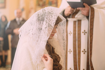 Bride in white veil at the church during a wedding ceremony