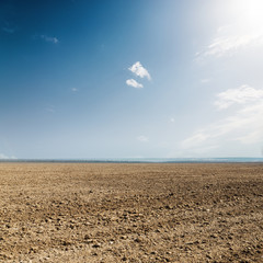 plowed spring agriculture field under sun in clouds