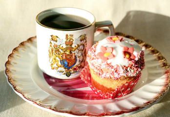 Vintage cup with tea and cupcake decorated with flower