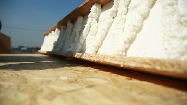 Worker applying polyurethane expanding foam glue with gun applicator. building houses of foam panels and plywood