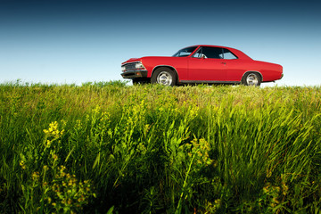Retro red car standing on asphalt road at sunset