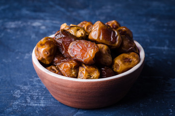 Fresh dates in clay bowl on stone background. Selective focus