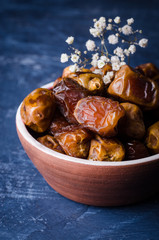 Fresh dates in clay bowl on stone background. Selective focus