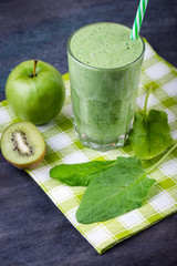 green smoothie with spinach, kiw iand apple  on a dark background, selective focus