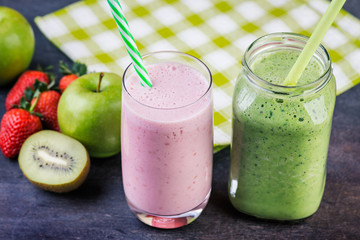 Strawberry and spinash smoothies in glasses with ingredients on dark background, selective focus.
