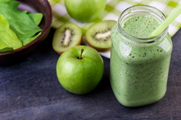 green smoothie with spinach, kiwi and apple in a jar  on a wooden table, selective focus