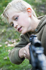 Portrait of little boy with airgun shooting outdoors, air rifle with telescopic sights