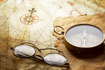 Vintage compass and glasses on antique map