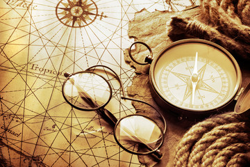 Vintage compass and glasses on antique map