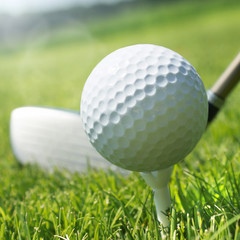 Golf club and ball on tee in grass