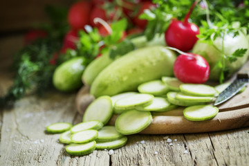 Round zucchini slices and fresh radish, vintage wooden backgroun