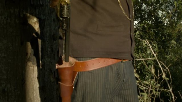 A cowboy from the American wild west era draws his black powder pistol ready to defend himself.