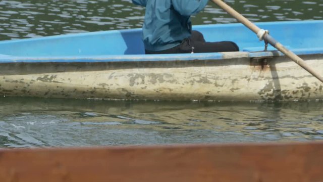 Man is rowing near the pier and departure with his small wooden boat.