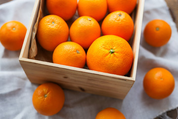 Box full of fresh oranges. Fruit harvest on rustic wooden table.