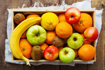 Box full of fresh fruits. Fruit harvest - apples, oranges, lemon, banana, kiwi.