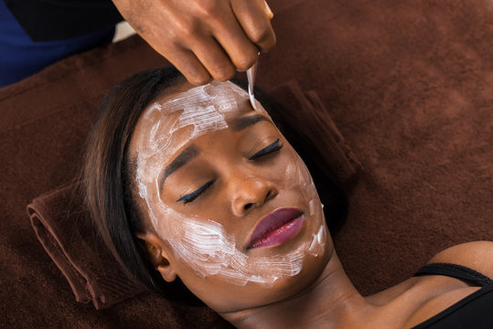 African Woman Applying Facial Mask In Spa