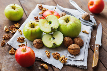 Healthy snack background - fruits and nuts. Green and red apples, raisins and walnuts on rustic wooden background.