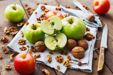 Healthy snack background - fruits and nuts. Green and red apples, raisins and walnuts on rustic wooden background.