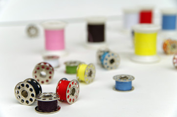 Metal bobbin spools with colorful thread arranged in white background