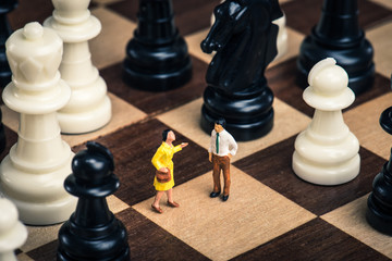チェス盤の上に立っているミニチュアの人間.男女関係