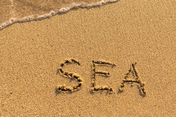 Sea - inscription by hand on the beach.