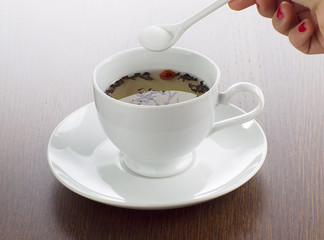 close-up shot of person holding spoon with lime tea on table.