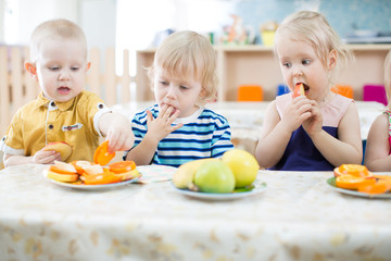 Tree funny kids eating fruits in day care centre